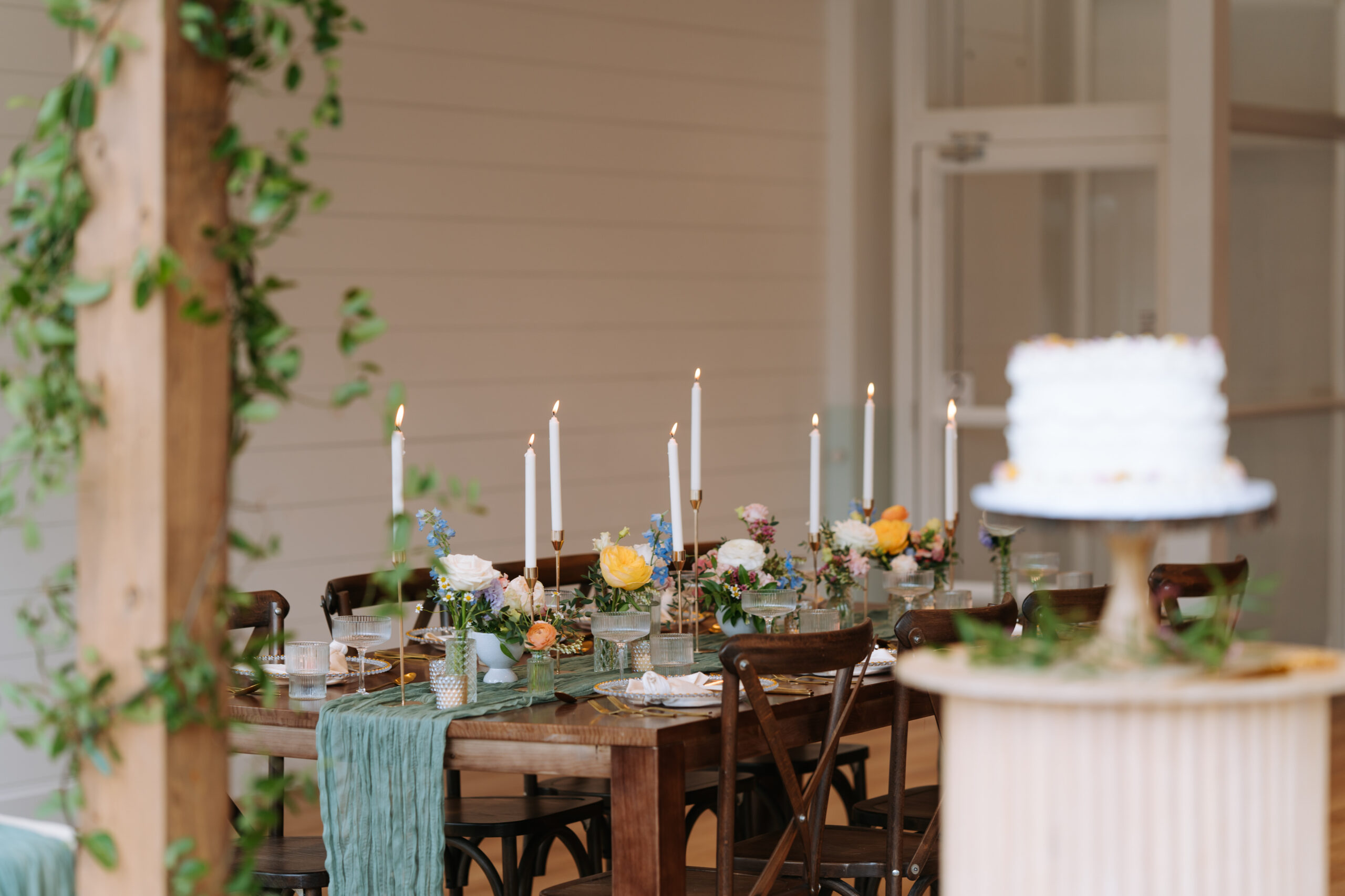 Elegant wedding tablescape with taper candles, spring florals, and a soft green runner at The Gem in Canmore.