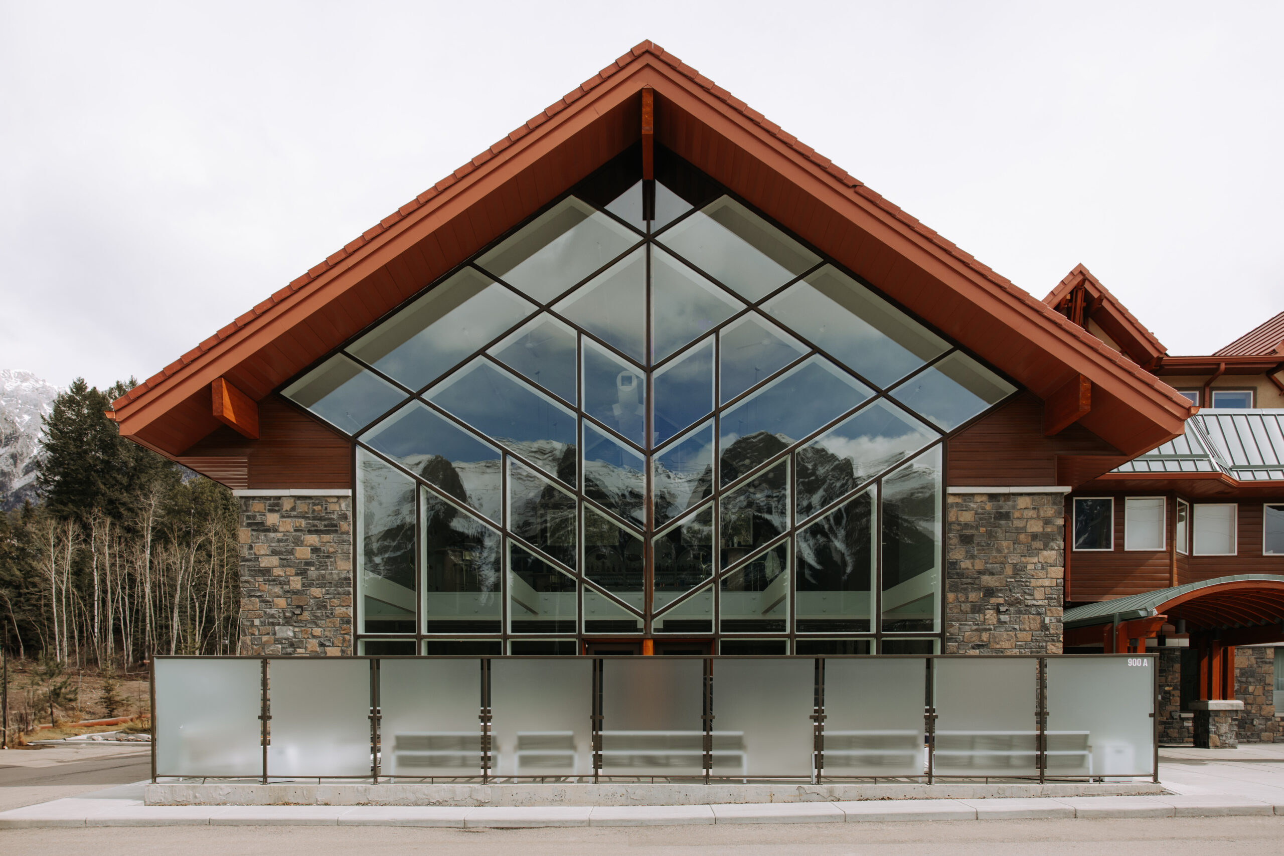 Exterior shot of The Gem in Canmore with its iconic glass front reflecting the surrounding mountain peaks.