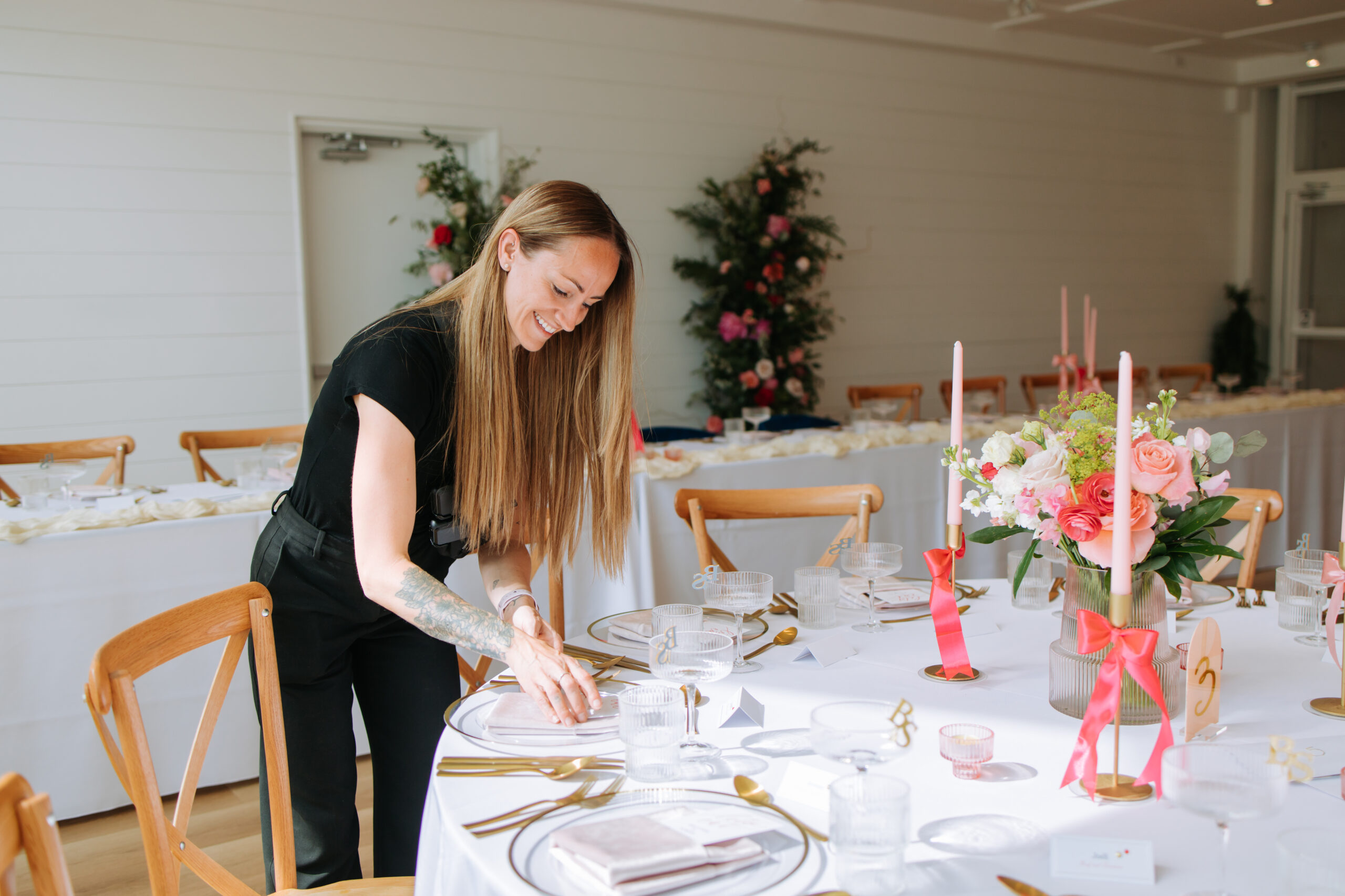 A wedding planner at The Gem carefully placing table settings during a bright, floral reception setup.