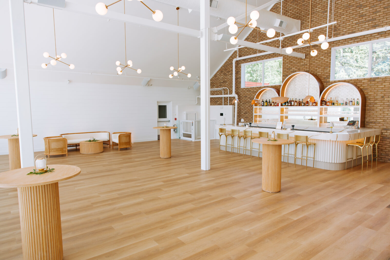 A wide view of The Gem's modern reception space featuring warm wood tones, sculptural lighting, and a white marble bar.