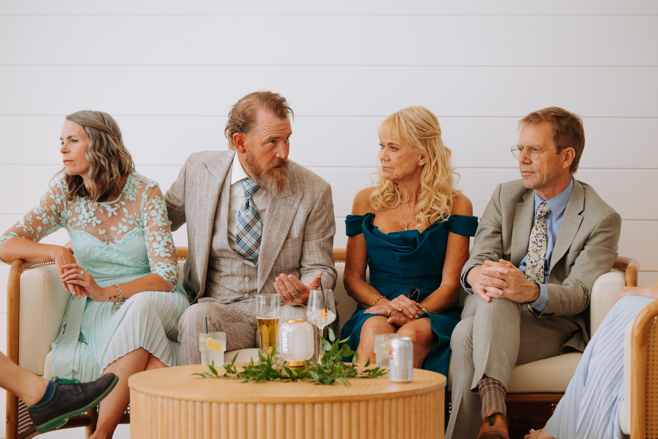 A group of well-dressed wedding guests chat while seated around a low table in The Gem’s lounge area.